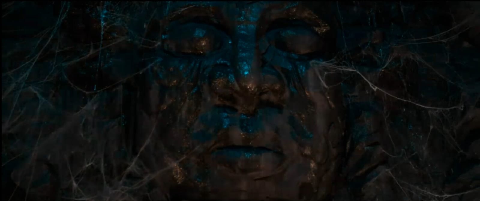 Giant ancient face with teal-gold shimmer